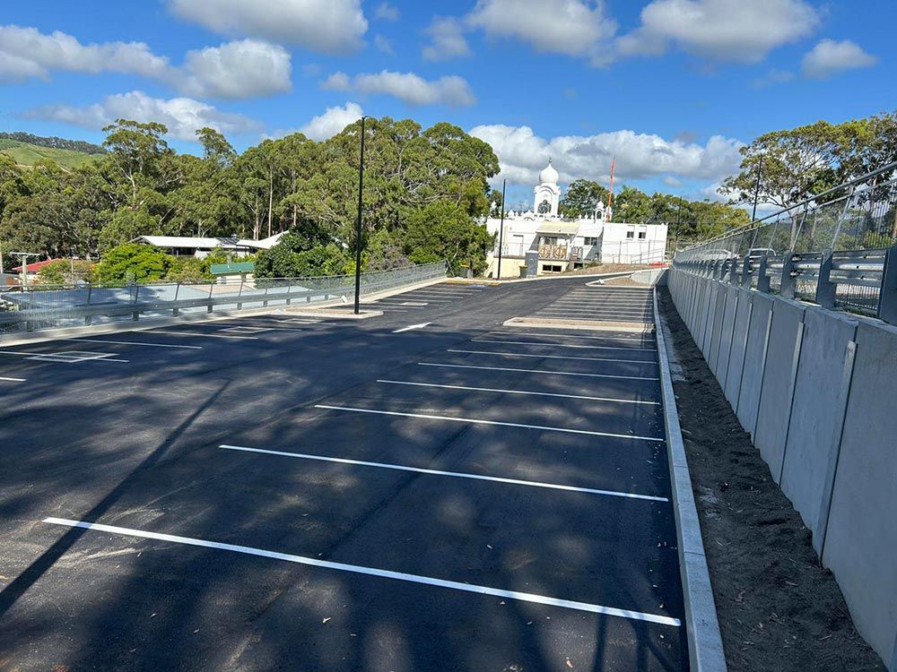 A Parking Lot With a Fence and a Building in the Background — North Coast Asphalts in Corindi Beach, NSW