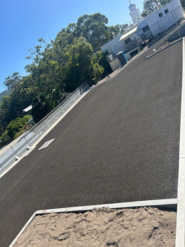 A Road With a White Building in the Background and Trees on the Side — North Coast Asphalts in Corindi Beach, NSW