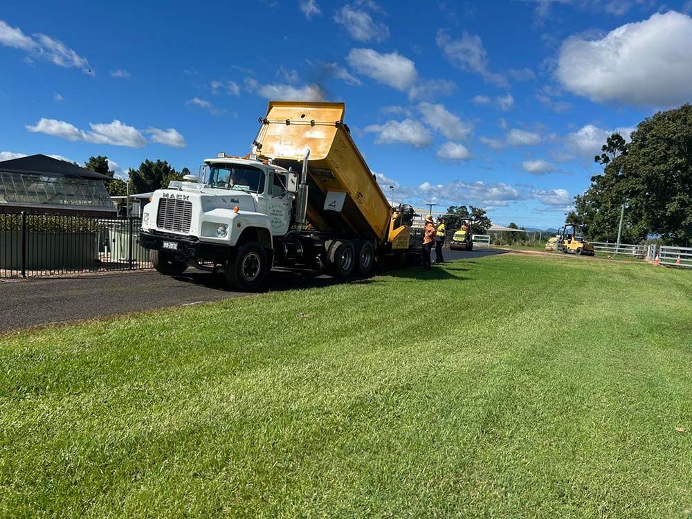 A Dump Truck is Parked in a Grassy Field — North Coast Asphalts in Corindi Beach, NSW