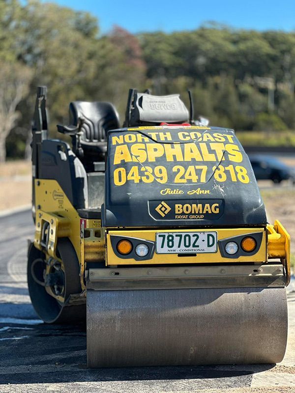 A Yellow and Black Asphalt Roller is Parked on the Side of the Road — North Coast Asphalts in Corindi Beach, NSW