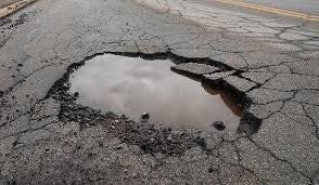 A Large Pothole in the Middle of a Road With a Puddle of Water in It — North Coast Asphalts in Corindi Beach, NSW