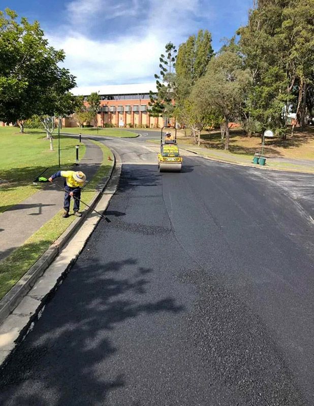 A Man is Laying Asphalt on the Side of a Road — North Coast Asphalts in Corindi Beach, NSW