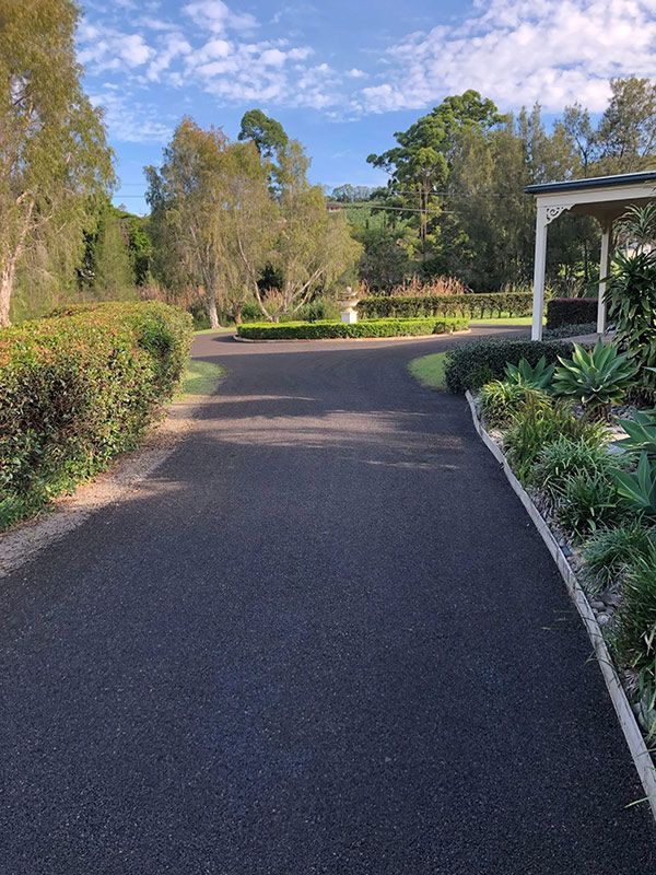 A Driveway Leading to a House Surrounded by Trees and Bushes — North Coast Asphalts in Corindi Beach, NSW