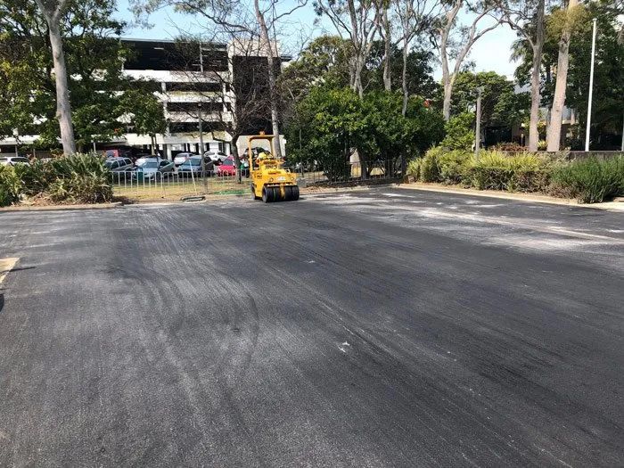 A Yellow Truck is Driving Down a Parking Lot — North Coast Asphalts in Corindi Beach, NSW