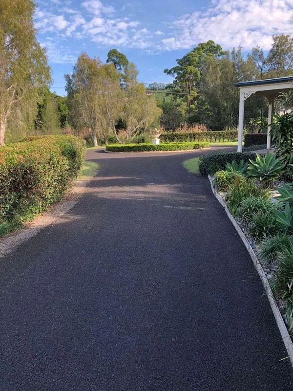 A Driveway Leading to a House Surrounded by Trees and Bushes — North Coast Asphalts in Corindi Beach, NSW