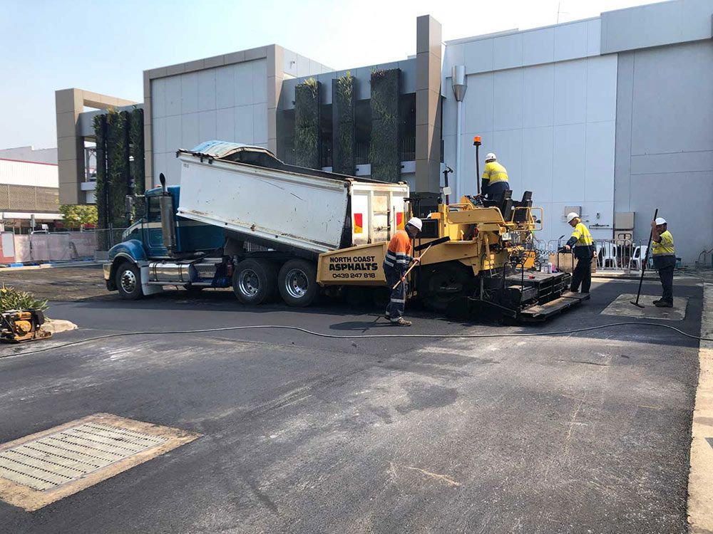 A Dump Truck is Being Loaded With Dirt in Front of a Building — North Coast Asphalts in Corindi Beach, NSW