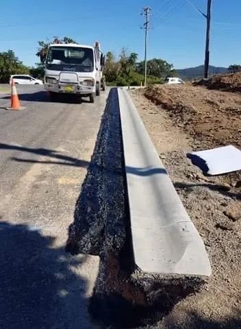 A Truck is Driving Down a Road Next to a Concrete Curb — North Coast Asphalts in Corindi Beach, NSW