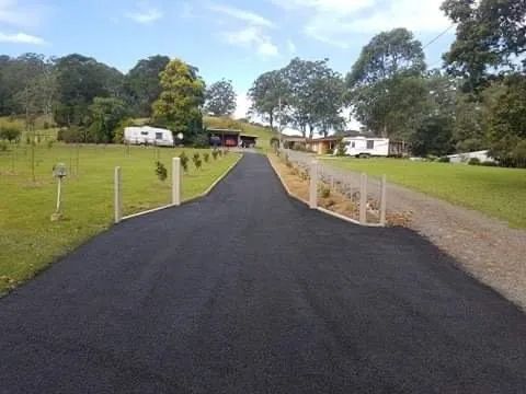 A Black Road Going Through a Grassy Field to a House — North Coast Asphalts in Corindi Beach, NSW