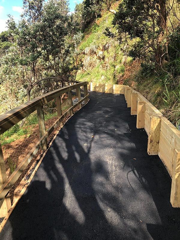 A Black Road With a Wooden Fence on the Side of It — North Coast Asphalts in Corindi Beach, NSW