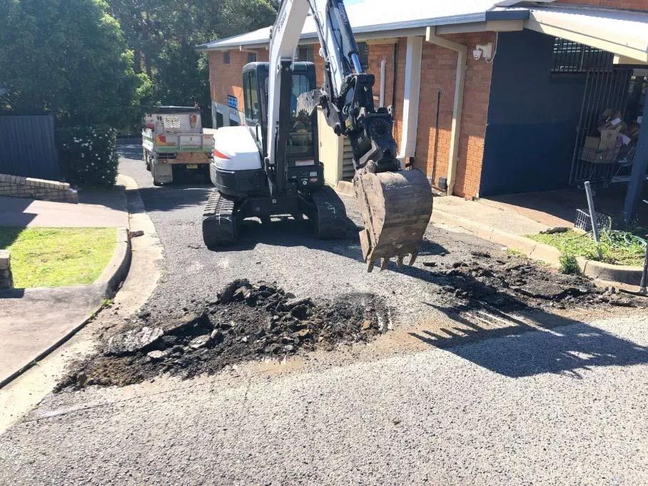 An Excavator is Digging a Hole in the Ground in Front of a House — North Coast Asphalts in Corindi Beach, NSW