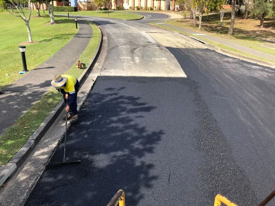 A Man is Raking Asphalt on the Side of a Road — North Coast Asphalts in Corindi Beach, NSW