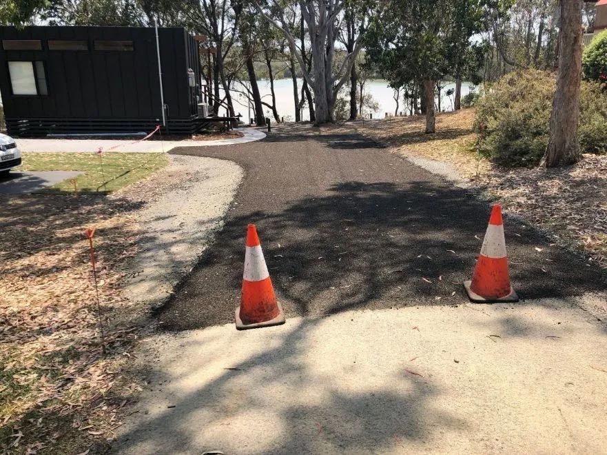 Two Orange and White Traffic Cones Are Sitting on the Side of a Road — North Coast Asphalts in Corindi Beach, NSW