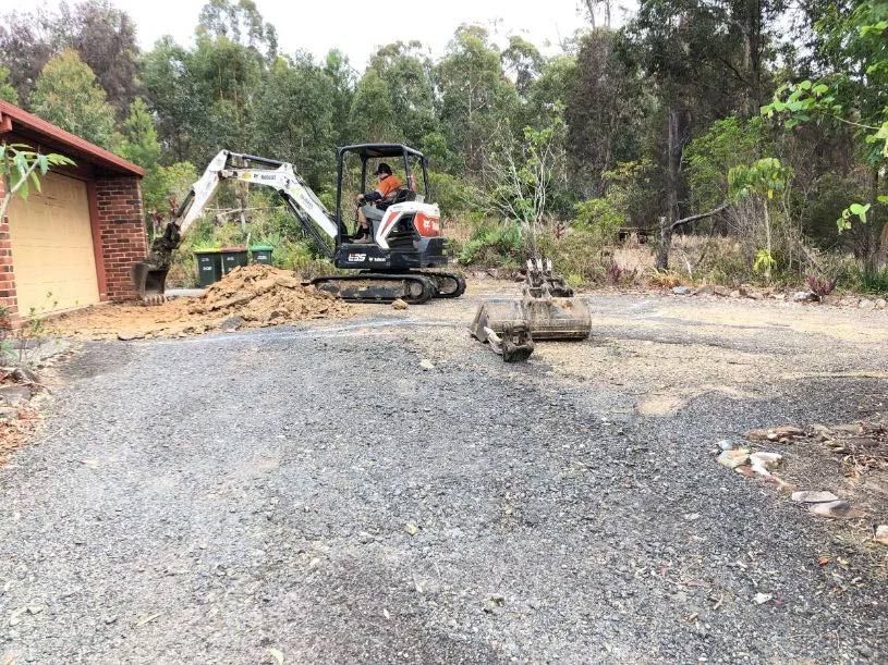 A Man is Driving a Small Excavator on a Gravel Road — North Coast Asphalts in Corindi Beach, NSW