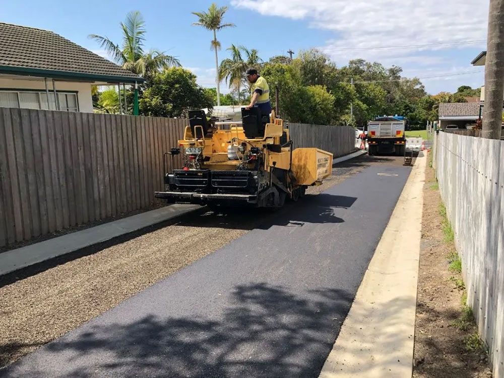 A Man is Driving a Yellow Machine on a Road — North Coast Asphalts in Corindi Beach, NSW