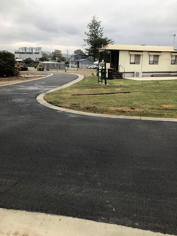 A House is Sitting on the Side of a Road Next to a Grassy Field — North Coast Asphalts in Corindi Beach, NSW