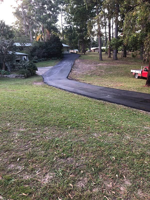 A Red Truck is Parked on the Side of a Road Next to a House — North Coast Asphalts in Corindi Beach, NSW