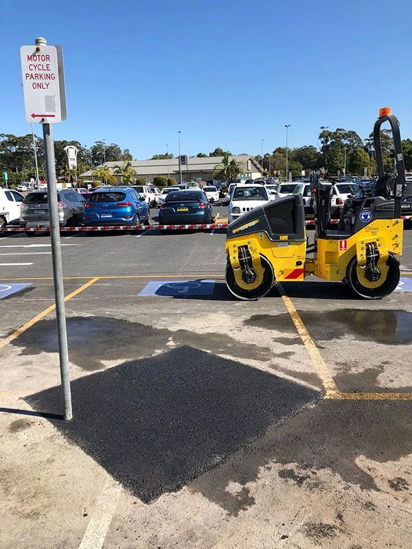 A Yellow Roller is Parked in a Parking Lot Next to a No Parking Sign — North Coast Asphalts in Corindi Beach, NSW