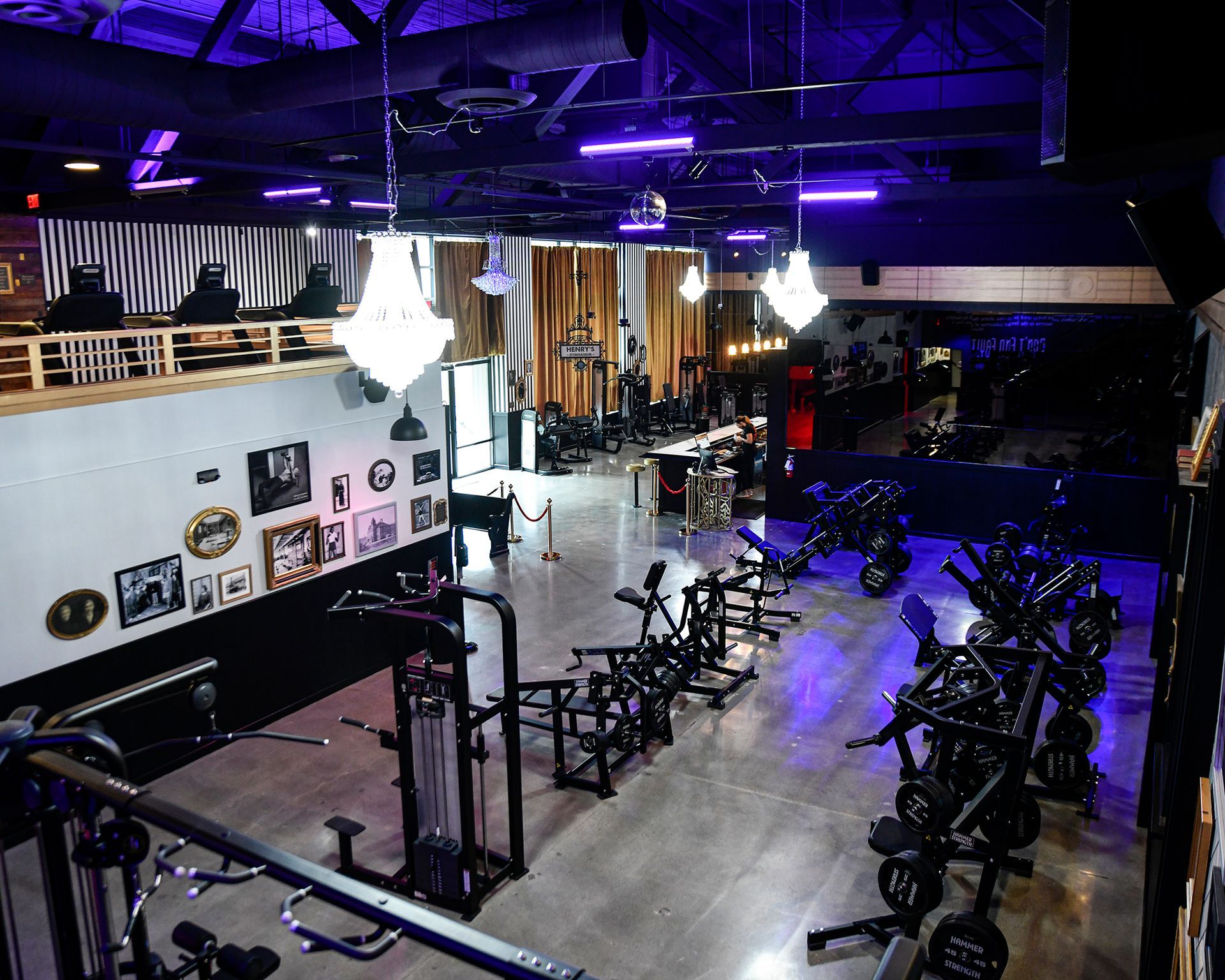 Henry’s Gymnasium Queen Anne training floor in Seattle with strength equipment, exposed beams, chandeliers, and purple lighting