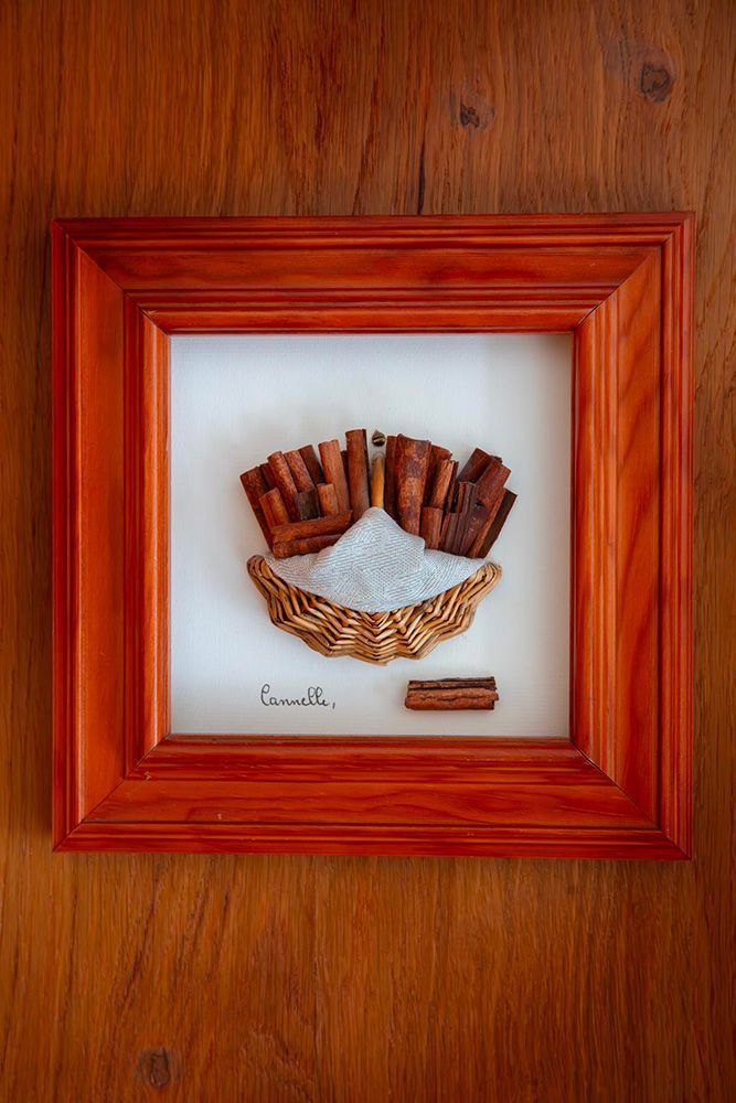 Cadre du chambre de l'Aubinière comprenant des bâtons de cannelle, du sucre et des gousses de graines de couleur dorée.