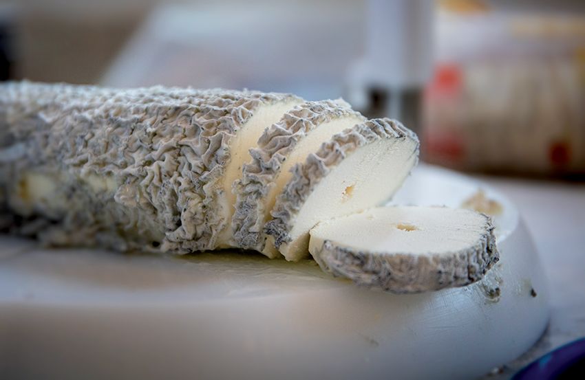 un morceau de fromage de sainte maure de Touraine est coupé sur une planche à découper.