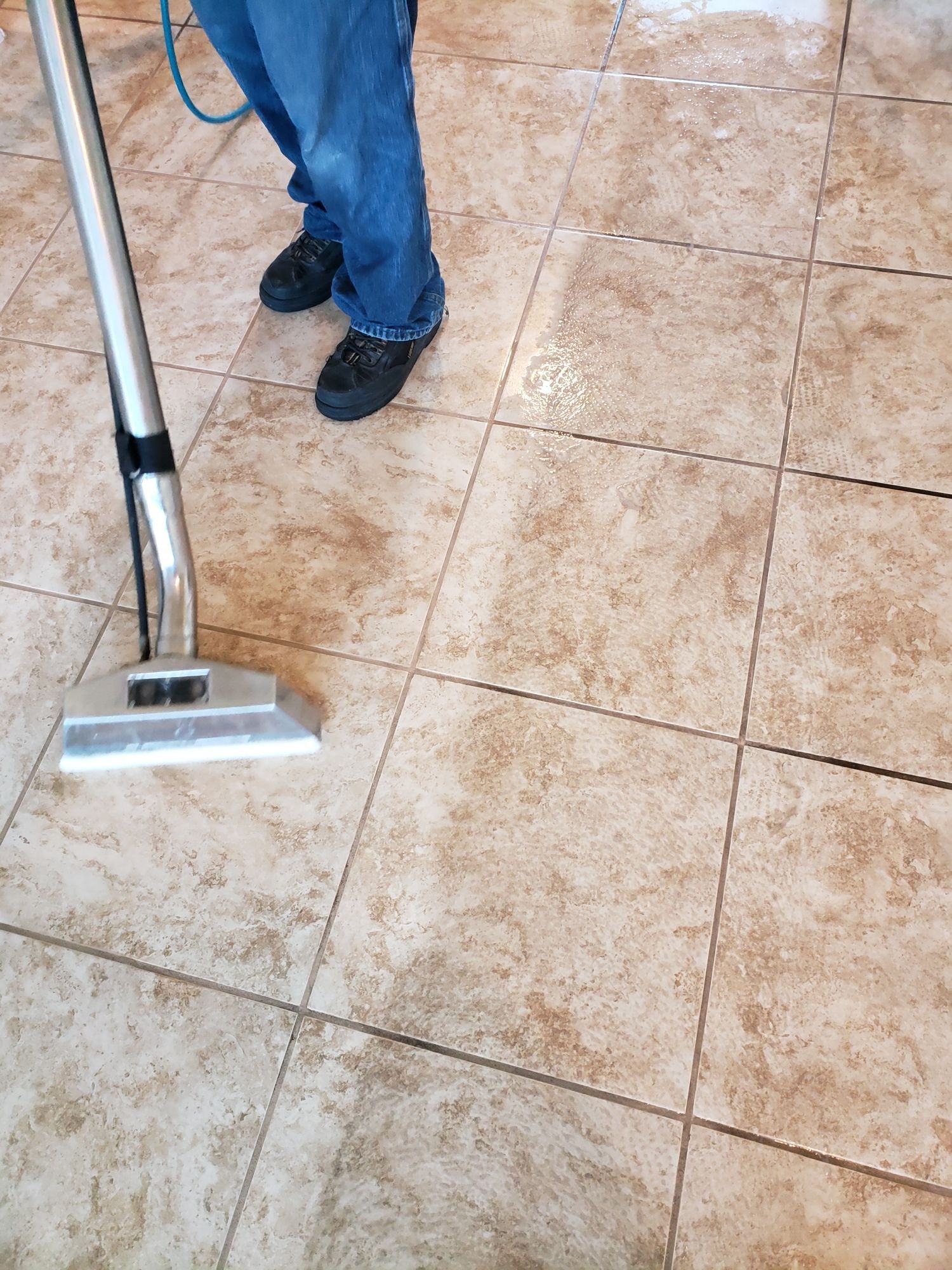 A person is cleaning a tile floor with a vacuum cleaner.