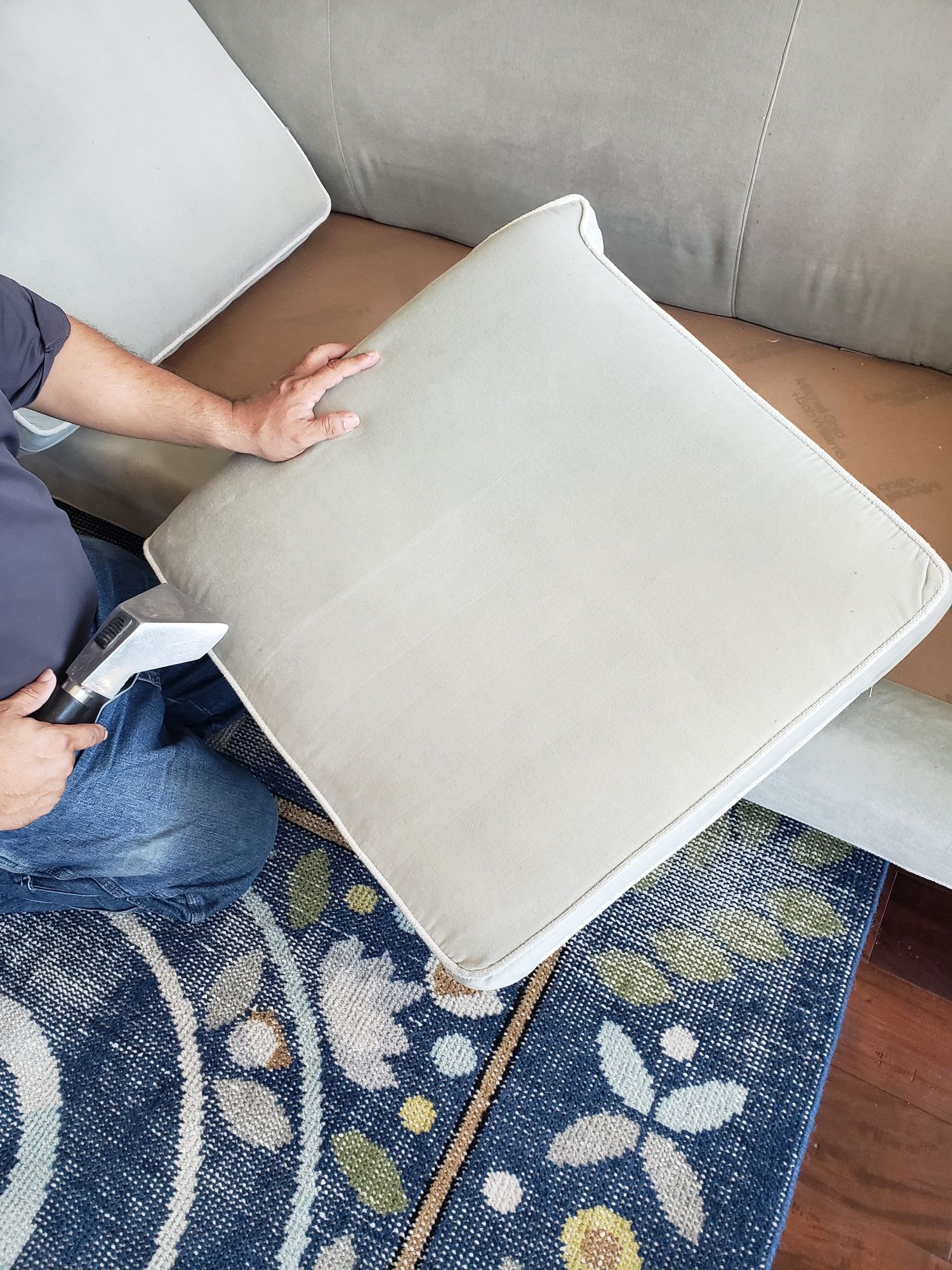 A person is sitting on a couch holding a pillow.