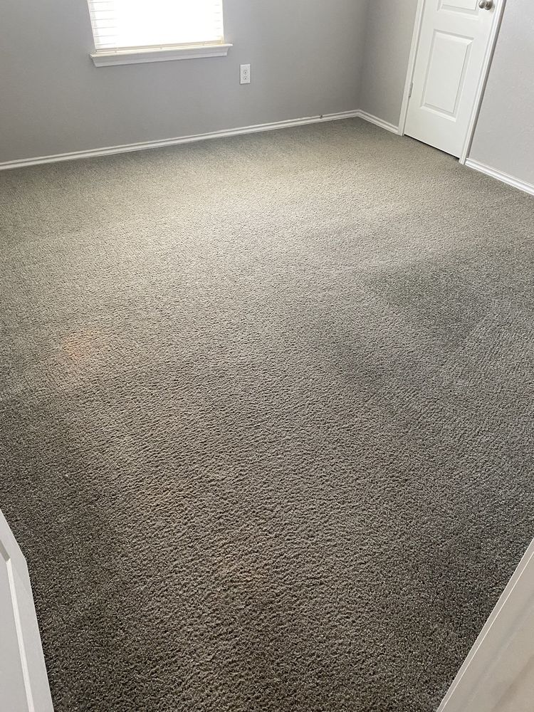 A bedroom with a large carpeted floor and a window.