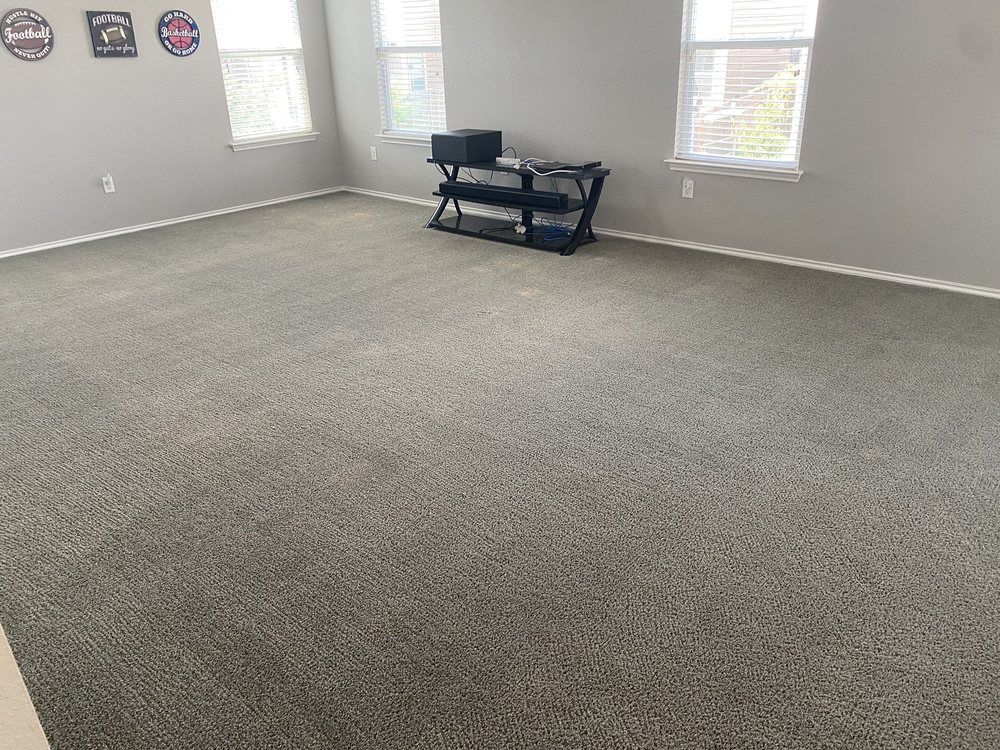 A large room with a carpeted floor and a television stand.