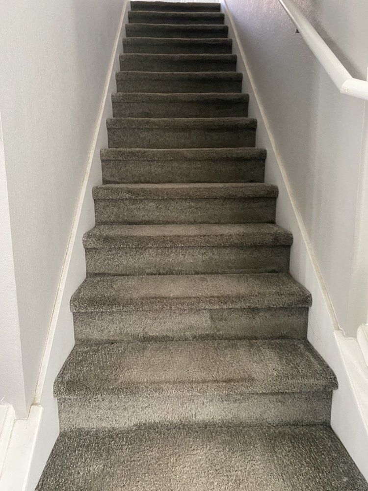 A set of stairs with a carpeted floor and a white railing.