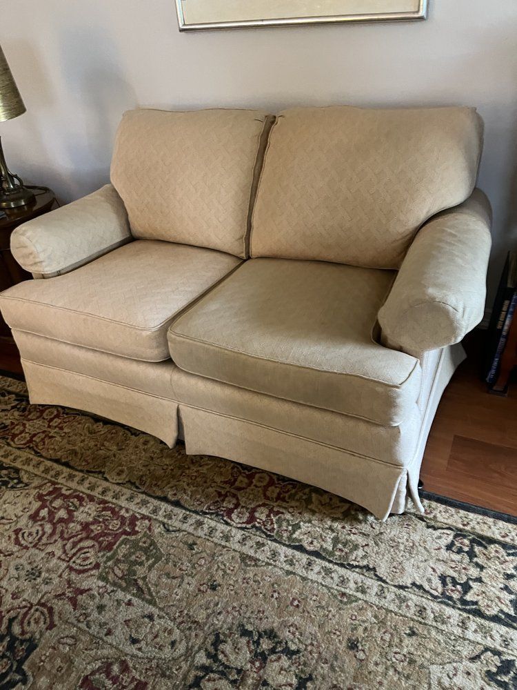 A beige couch is sitting on top of a rug in a living room.