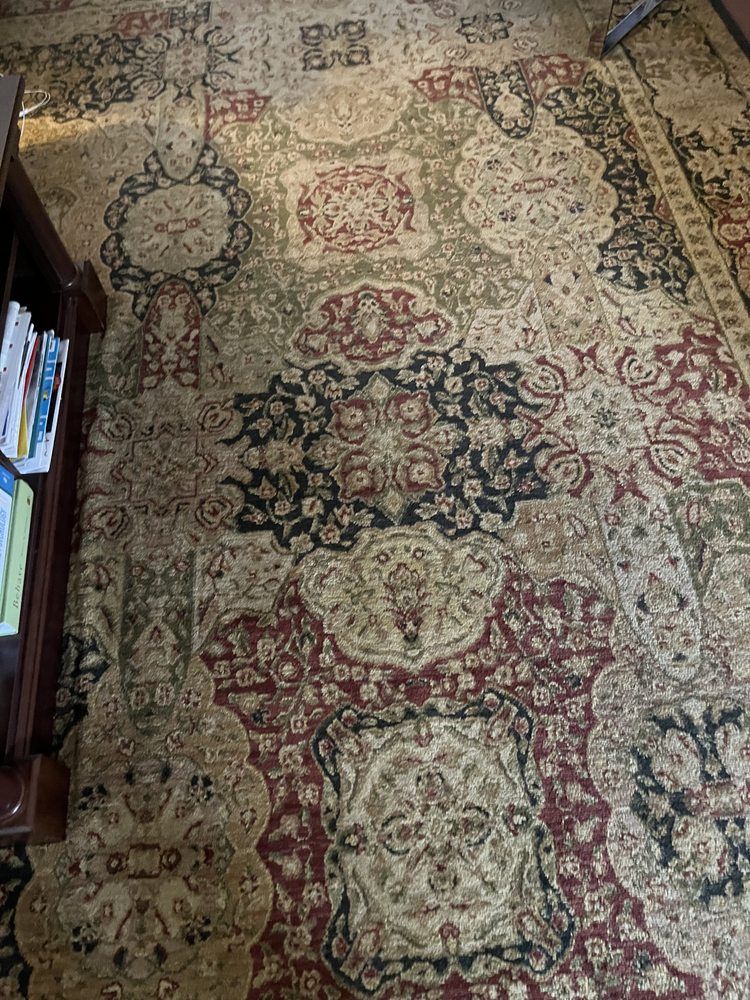 A rug is sitting on the floor in a living room next to a bookshelf.