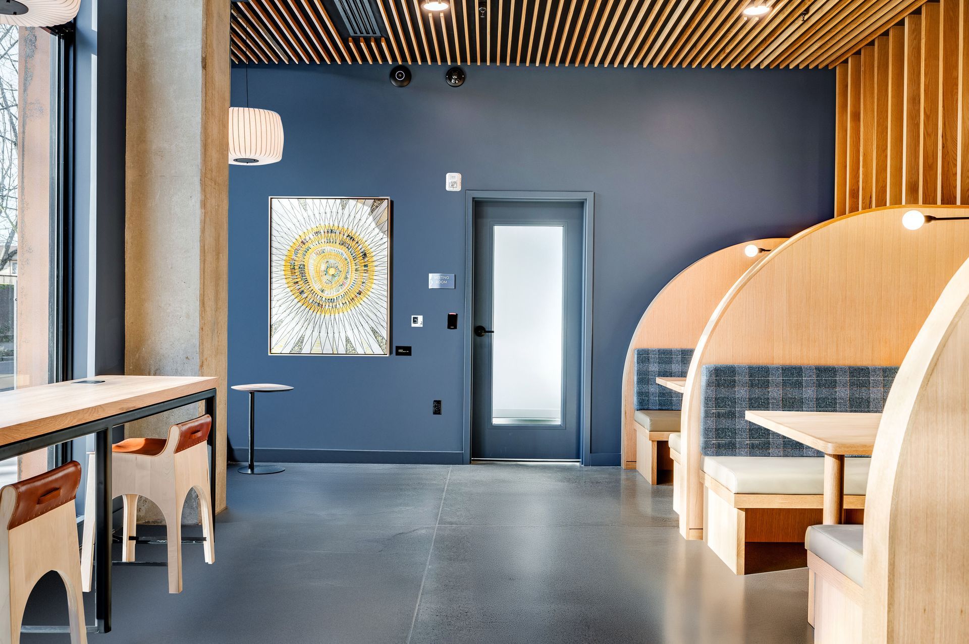 Modern cafe interior with booths, tables, and a blue wall with artwork.