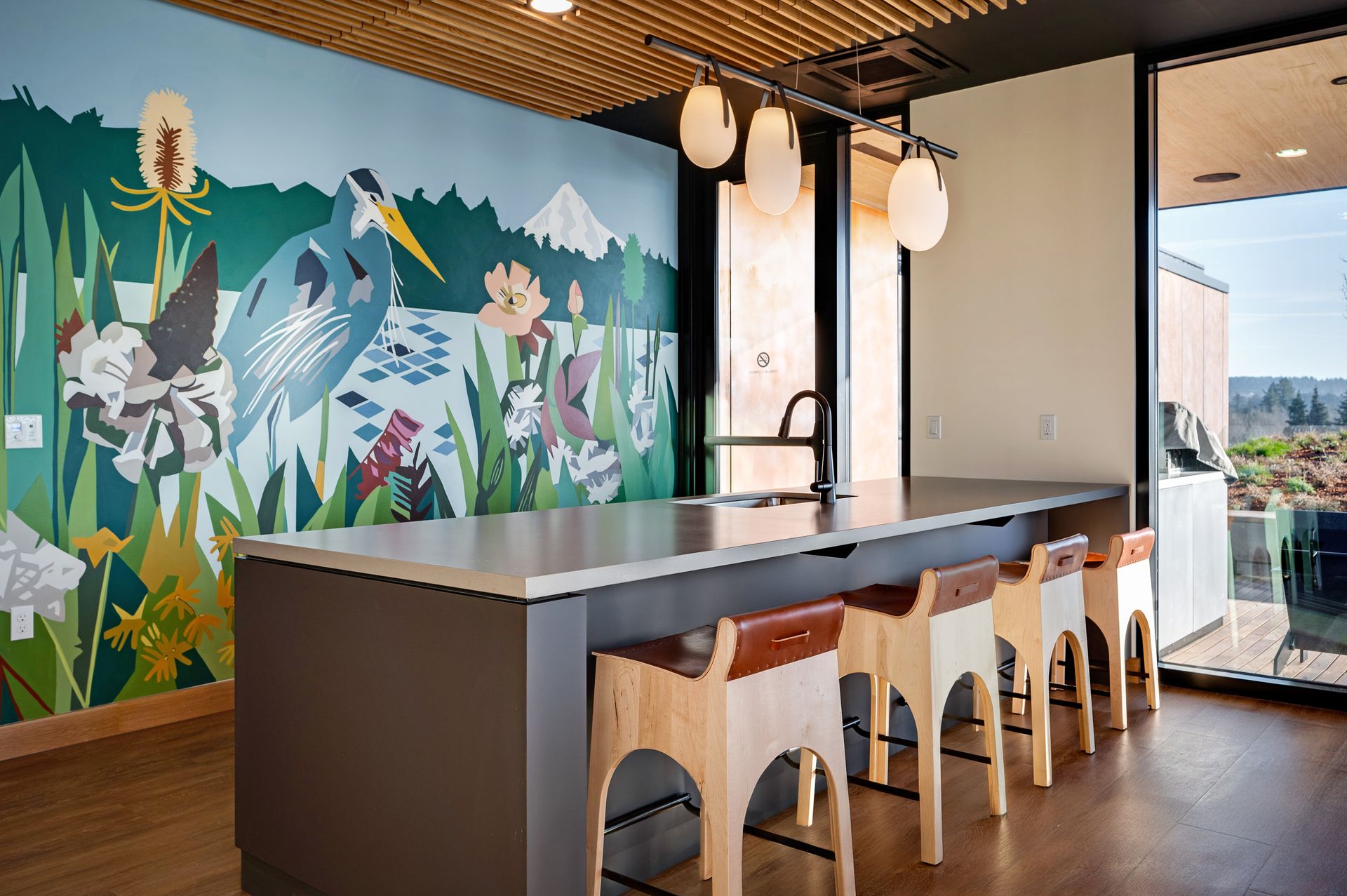 Kitchen with mural of heron, countertop, bar stools, and outdoor view.