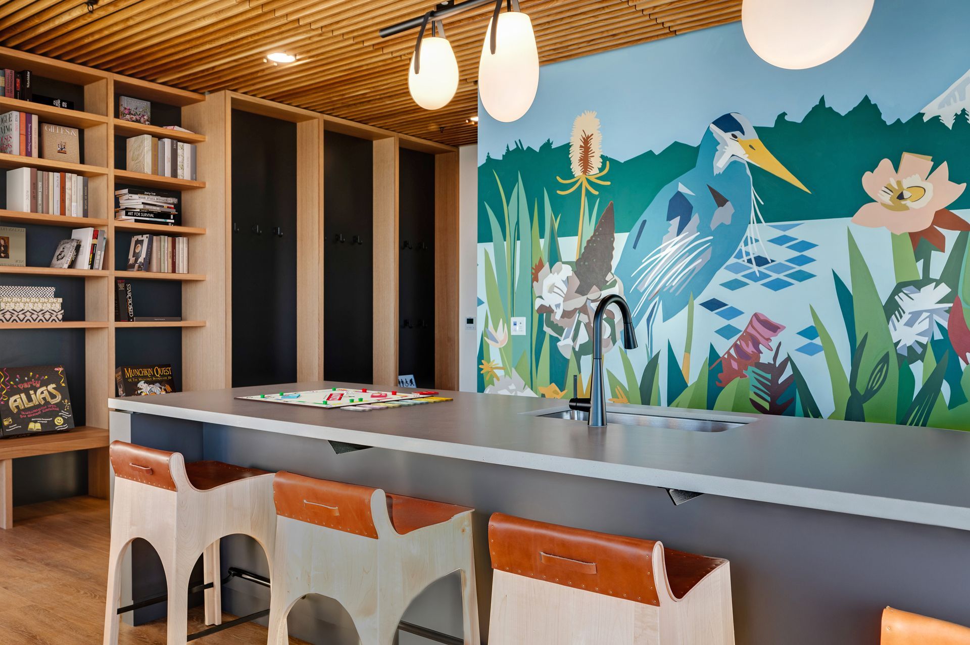 Kitchen with a mural of a blue heron, light wood cabinets, and bar stools.