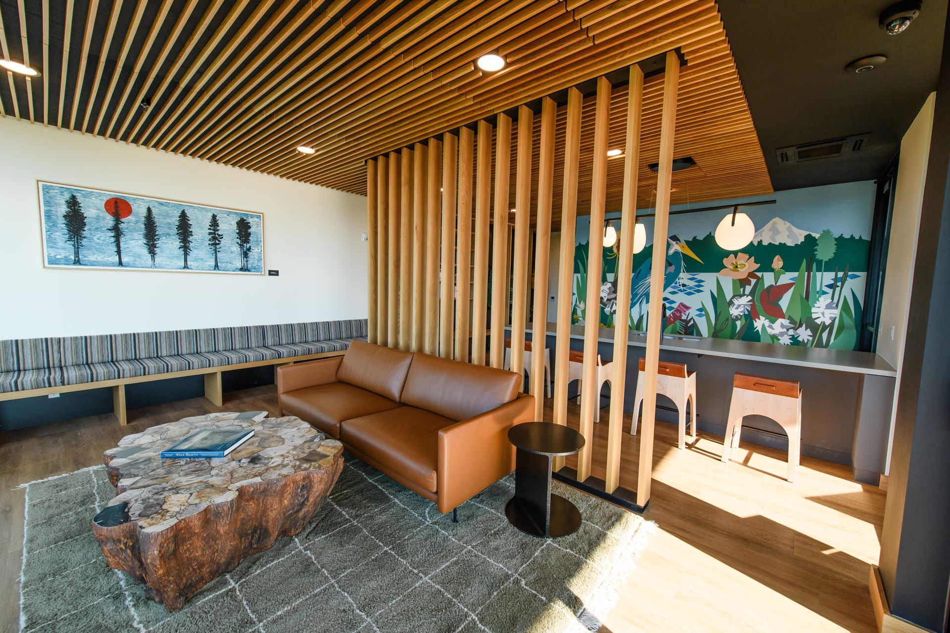 Waiting room with brown leather sofa, wooden dividers, and a tree stump coffee table.