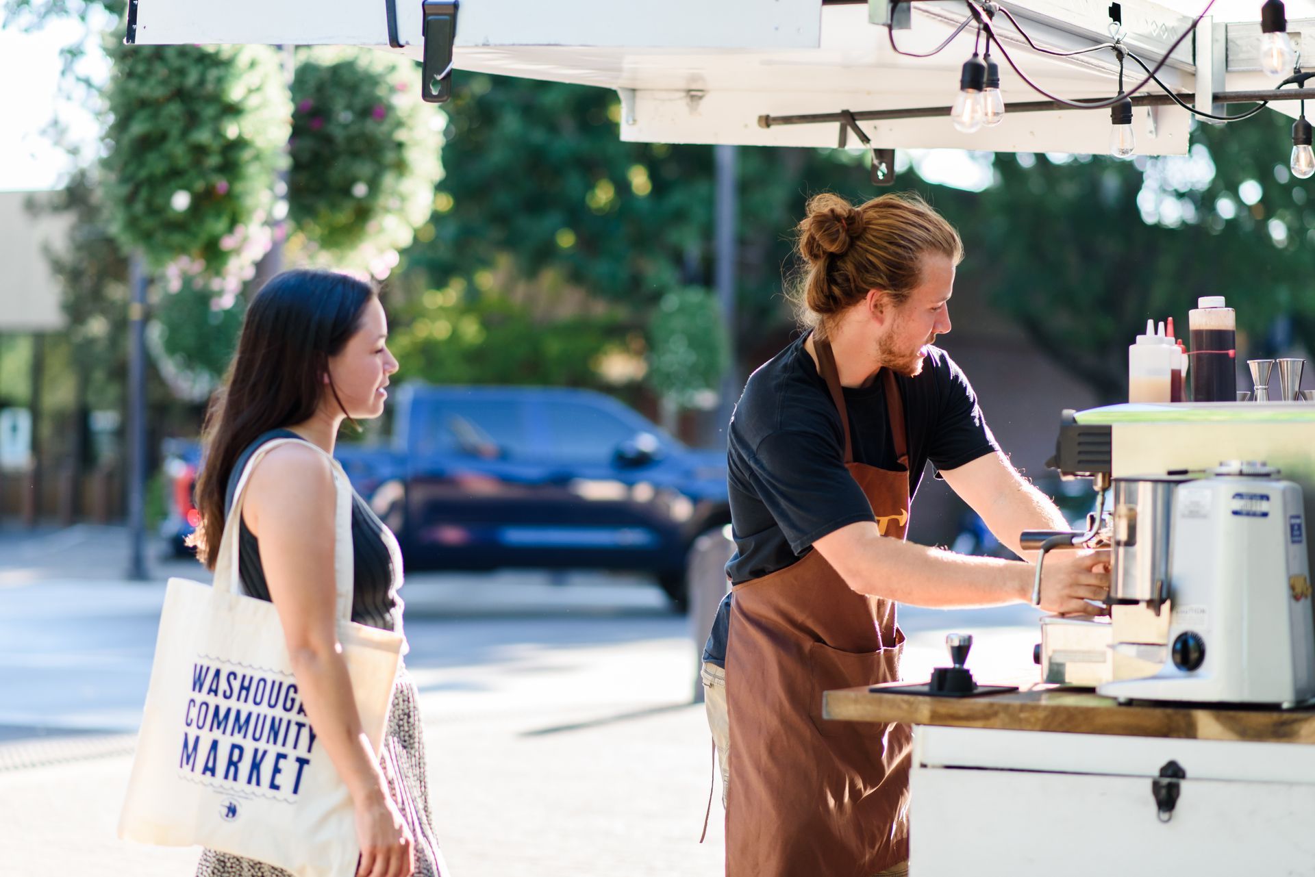 Woman sitting on a wooden bench, near a fire pit, overlooking a landscape.