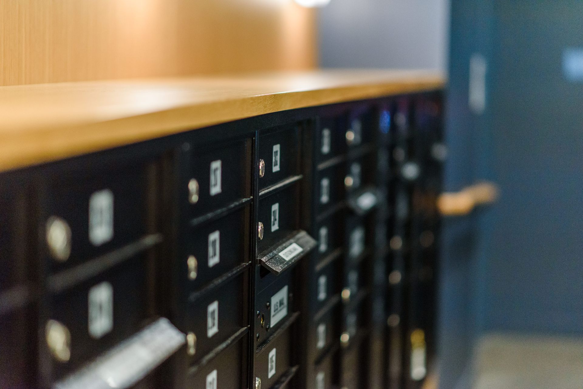 Row of black mailboxes, one open, with wooden trim.