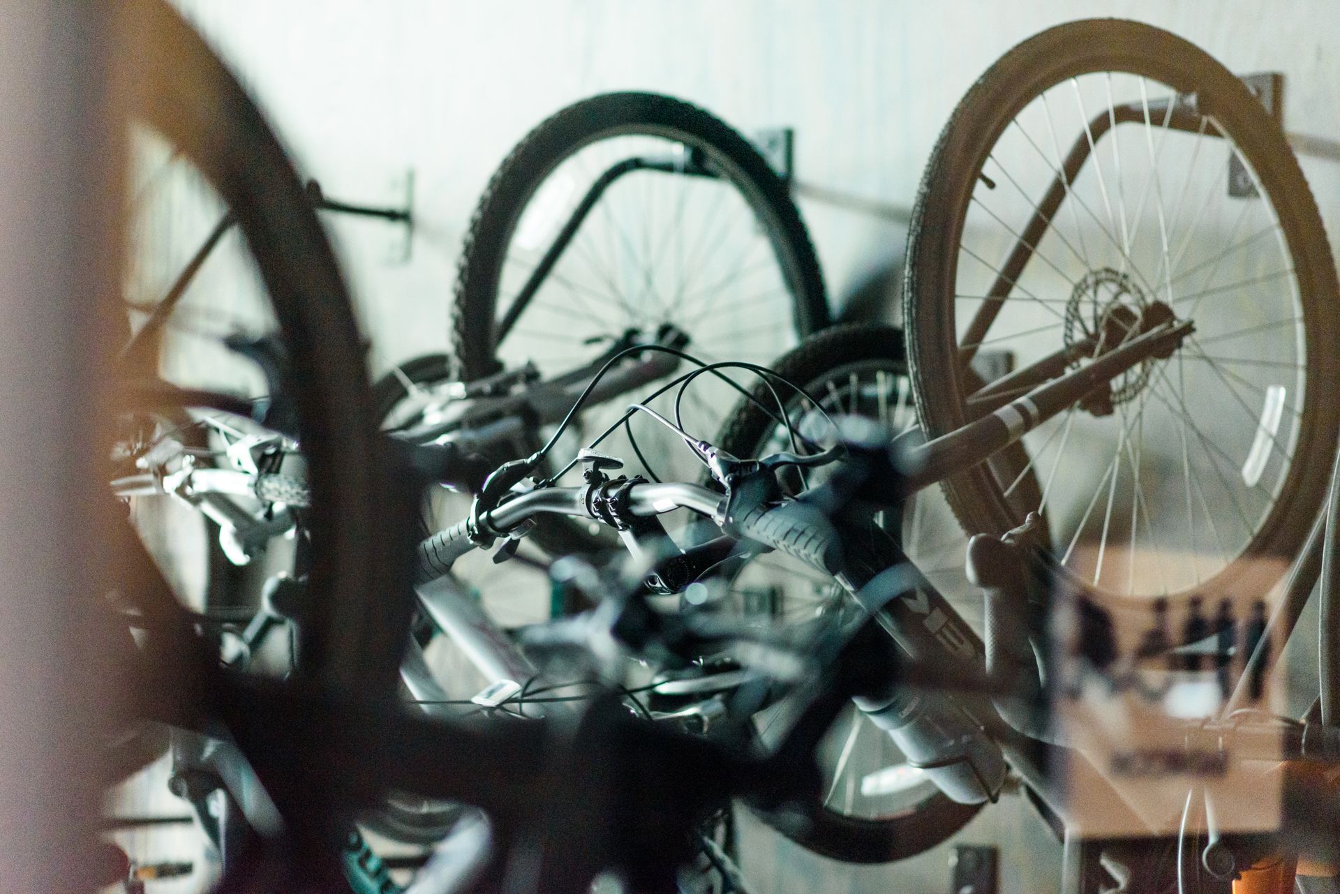 Bicycles hanging on a wall in a shop; wheels, handlebars, and other parts visible.