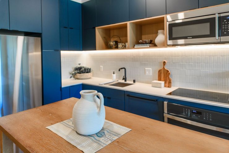 Blue and wood-toned modern kitchen with open shelving, stainless steel appliances, and a wooden island.