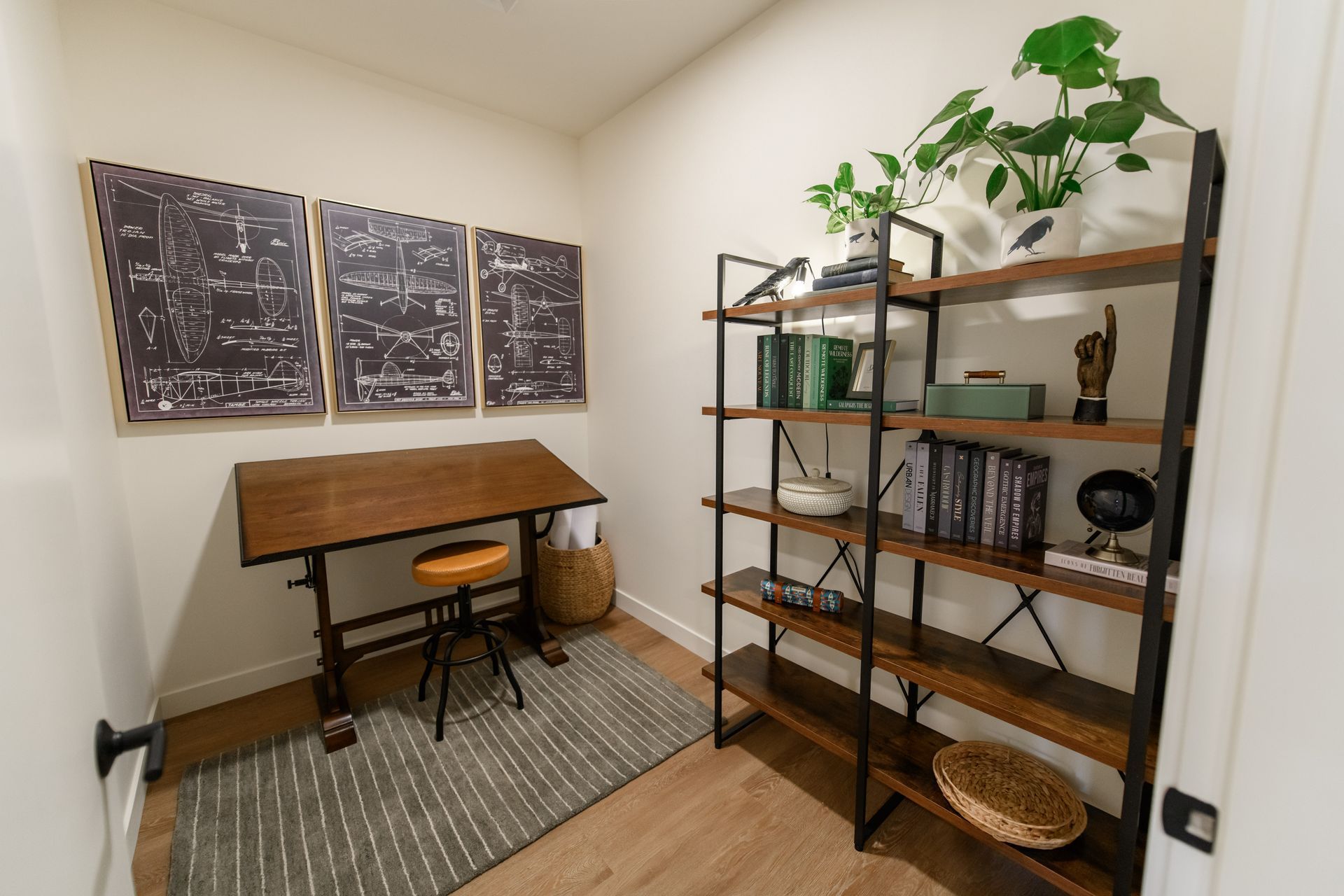 Small home office with a drawing desk, shelves, and potted plants.