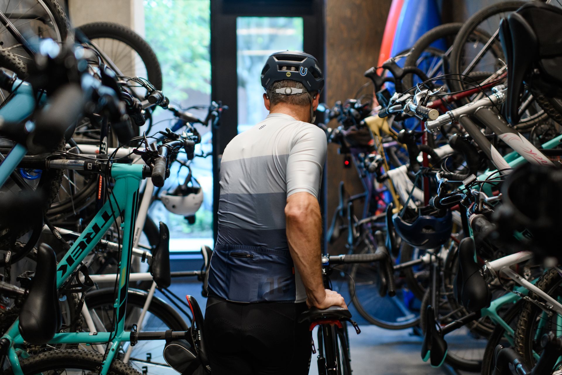Cyclist in cycling gear exiting a bike storage room, surrounded by parked bicycles.