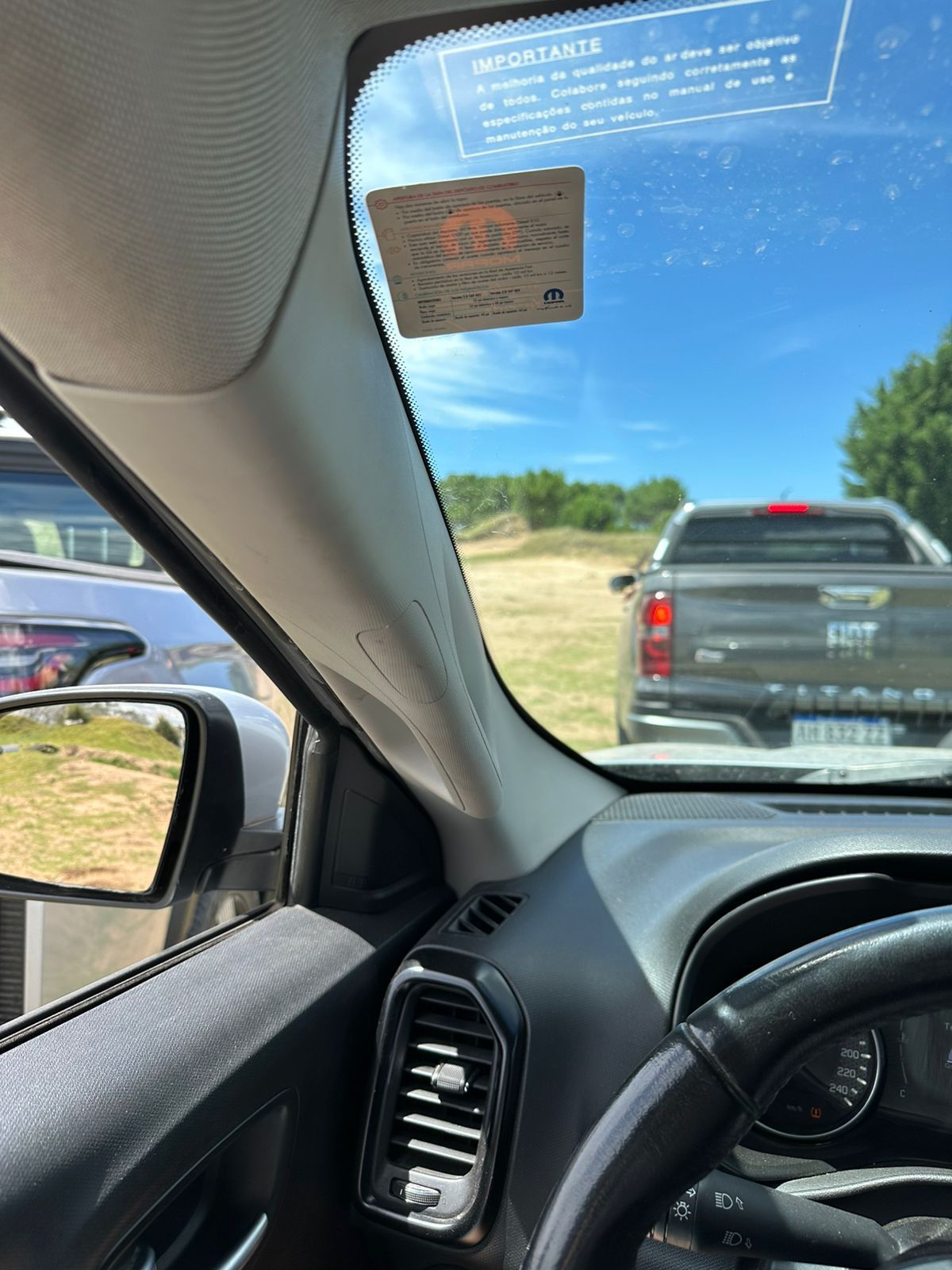 Vista del interior del automóvil, mirando dos camiones en un campo de hierba en un día soleado.