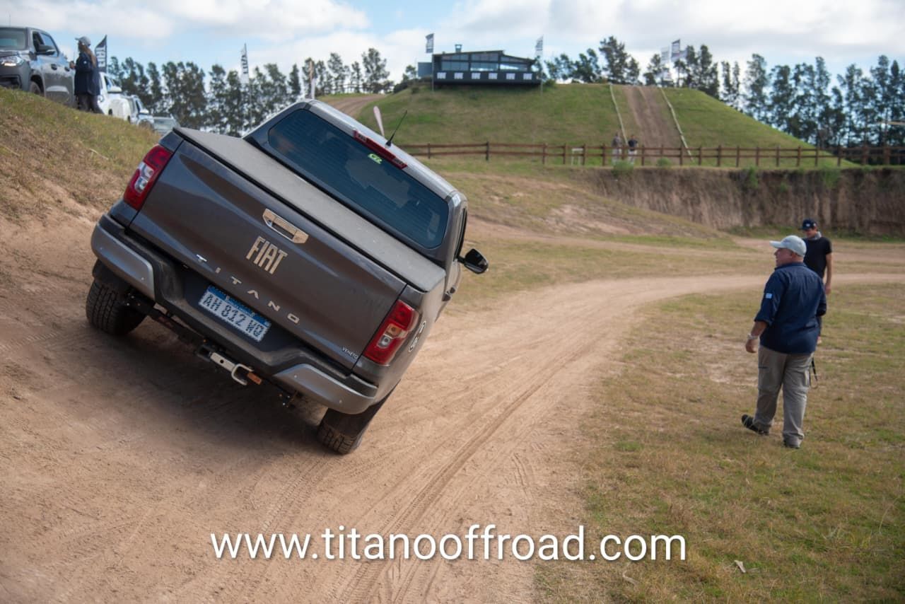 Una camioneta volcada en un camino de tierra mientras una persona se encuentra cerca en un terreno cubierto de hierba.