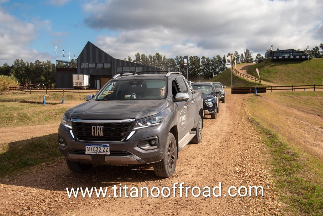 Convoy de camionetas grises circulando por un camino de tierra todoterreno bajo un cielo nublado.