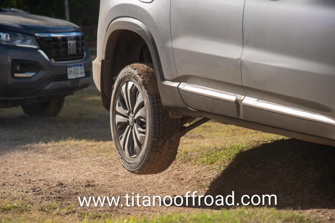 SUV plateado con neumáticos todoterreno sobre tierra cerca de otro vehículo, marca de agua de titanoffroad.com