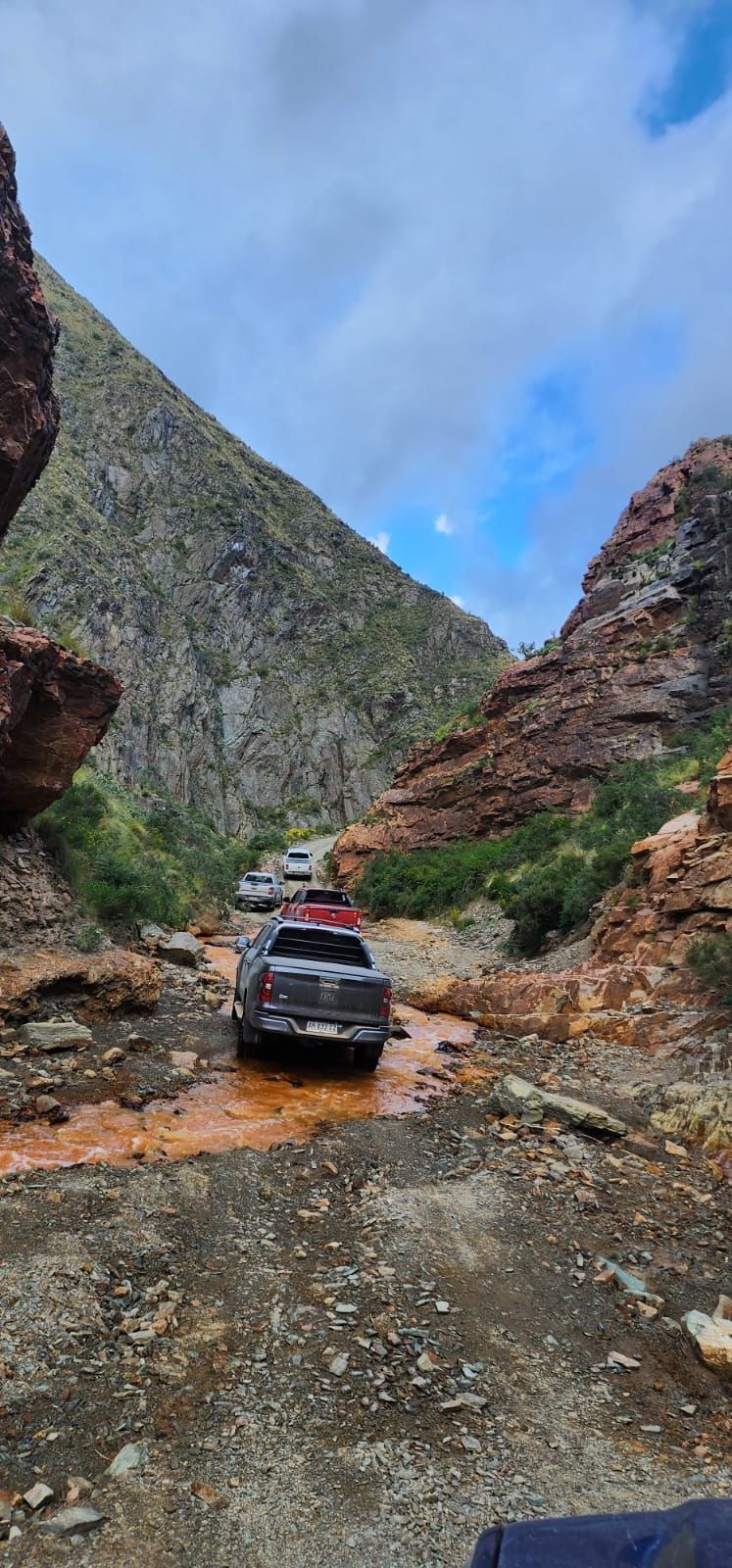 Una camioneta oscura circulando por un arroyo fangoso de color naranja 