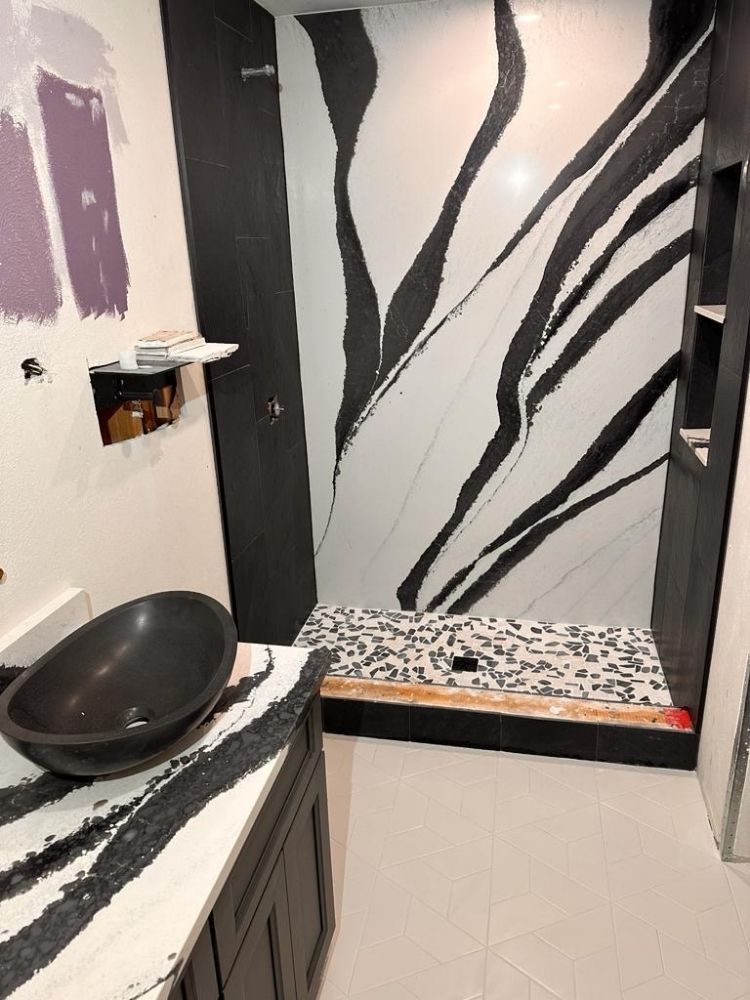 Modern bathroom vanity with black basin and matching shower featuring bold black and white abstract wall panels.