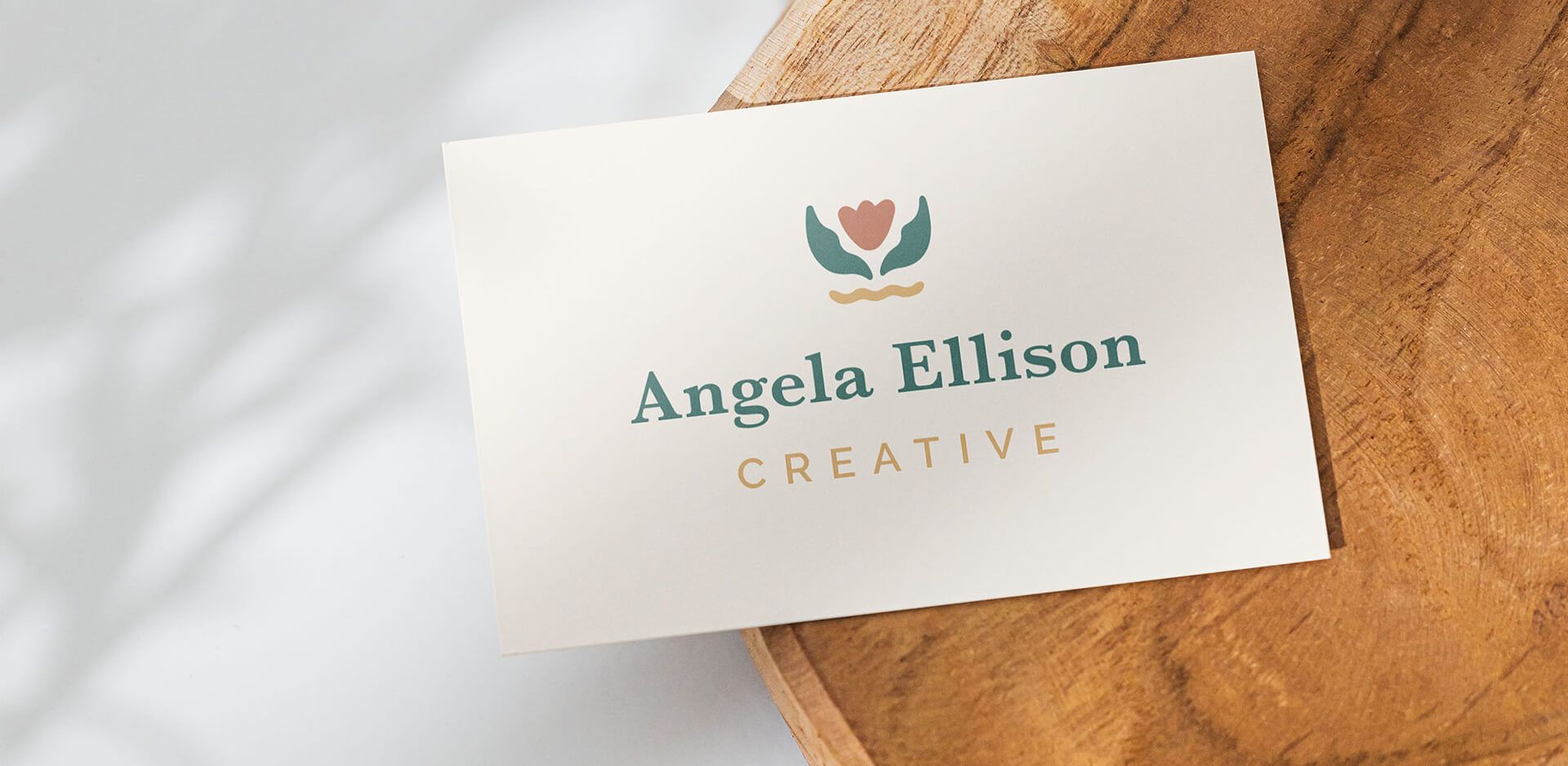 Front of Angela Ellison Creative's business card, sitting on top of a wood cookie.