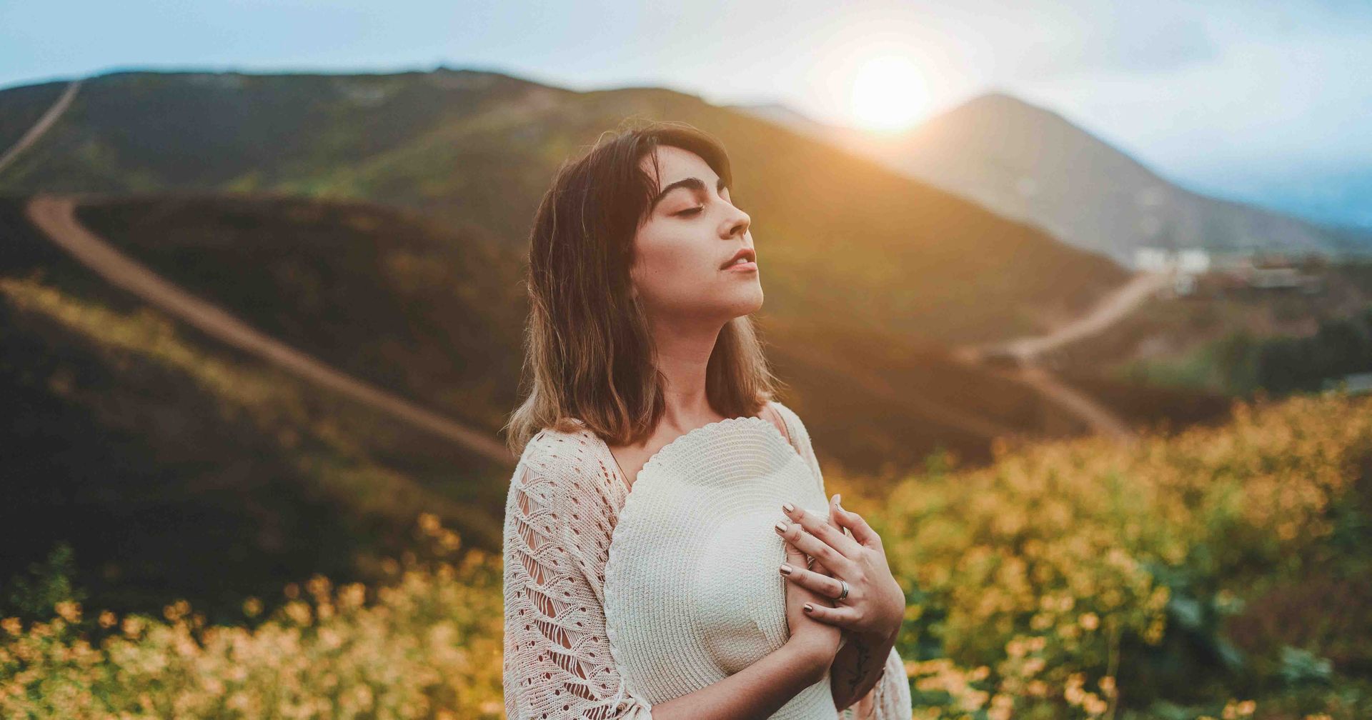 female founder at the top of a mountain with the sunrise to her back and wildflowers surrounding her