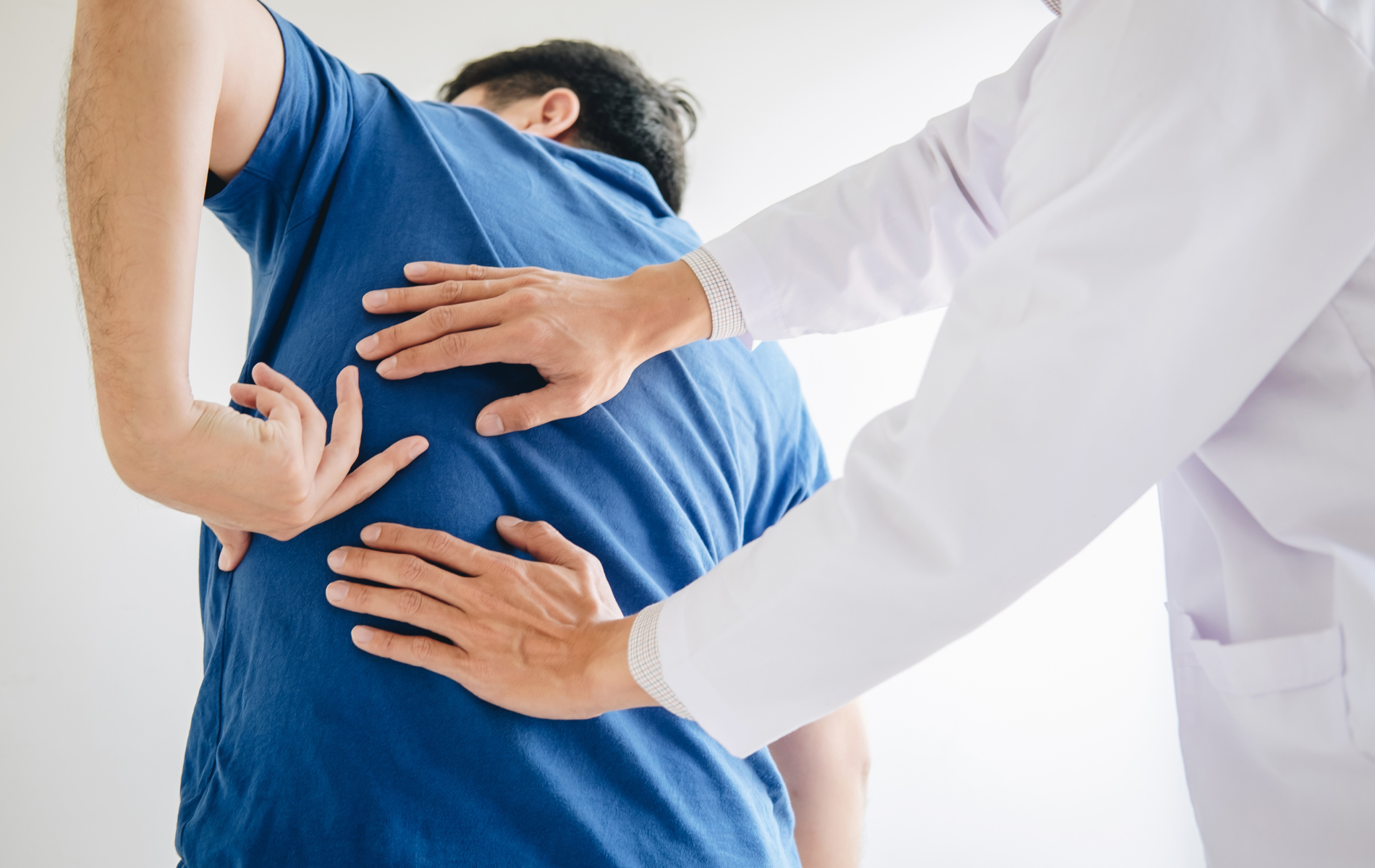 Doctor examining a patient's lower back; hands on back.
